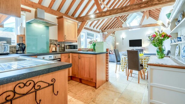 Una cucina moderna con travi in legno, un'area pranzo con tavolo e sedie, e vista all'esterno.