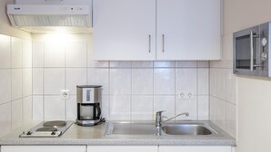Een moderne keuken met witte kastjes, een koffiezetapparaat, een magnetron en een spoelbak.