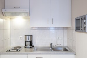 Eine moderne Küche mit weißen Schränken, einer Kaffeemaschine, einer Mikrowelle und einem Spülbecken.