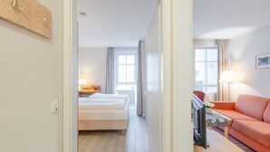 Een hotelkamer met een bed, een televisie, een bank en een raam met gordijnen.