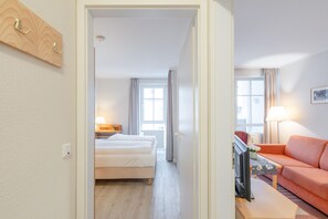 Ein Hotelzimmer mit Bett, Fernseher, Sofa und einem Vorhangfenster.
