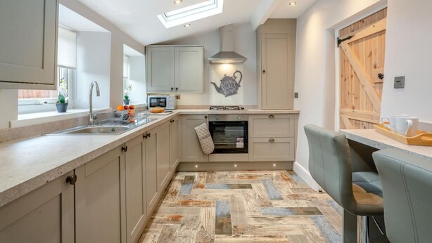 A modern kitchen with a herringbone floor pattern, a built-in oven, and a window providing natural light. - 2 Bed in Consett (oc-b42654) (Consett)