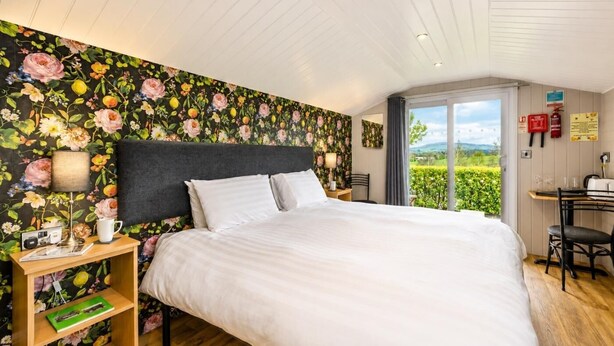 A bedroom with a large bed, a desk, and a view of the outdoors. - 1 Bed in Lancashire (oc-w37869) (Bentham)