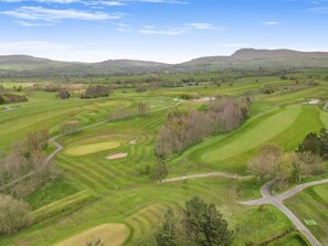 A golf course with multiple fairways, greens, and sand bunkers.