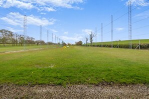 Ein grasbewachsenes Feld mit Stromleitungen und einem Kiesweg.