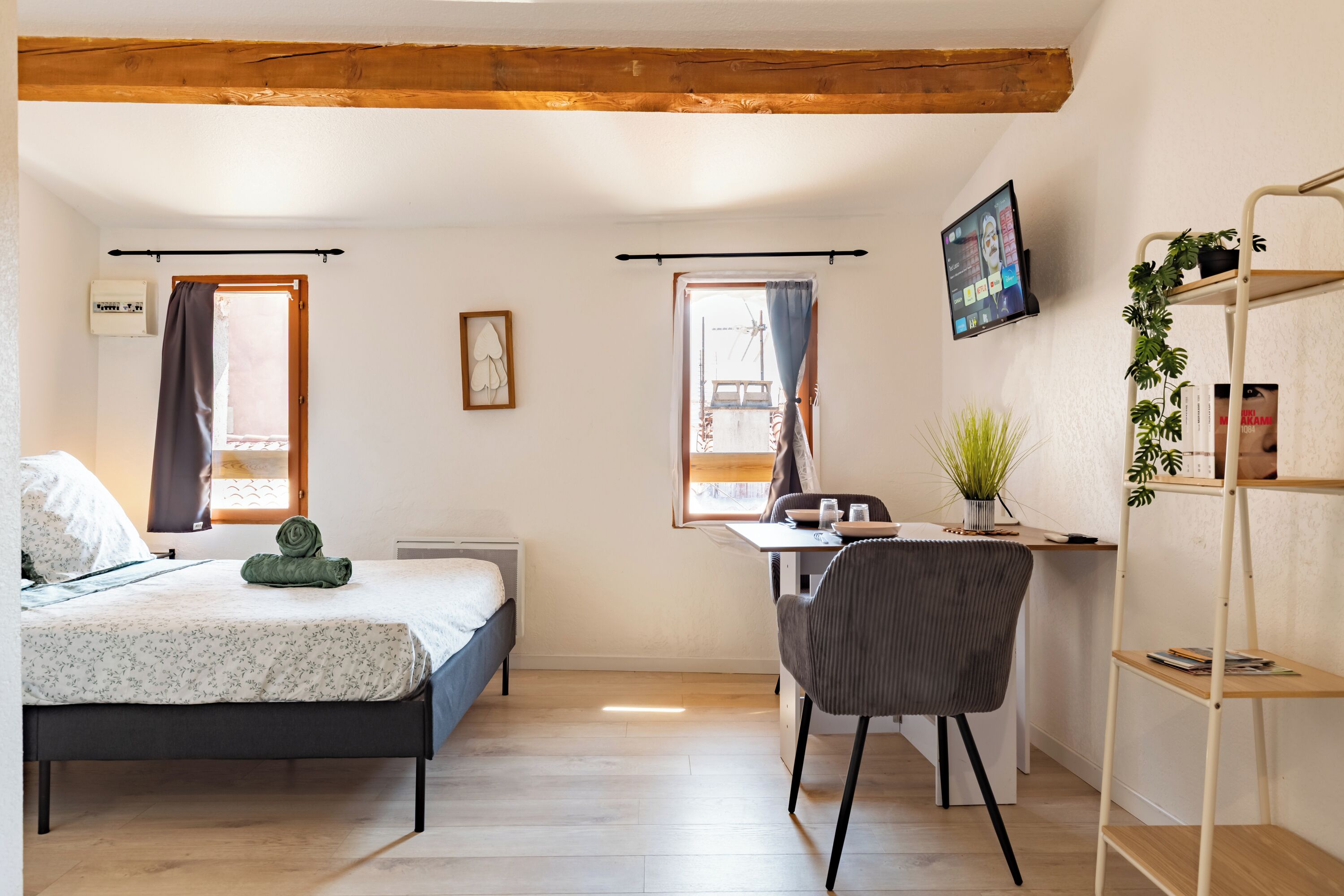 Quarto com cama, escrivaninha, cadeira, televisão e estante.