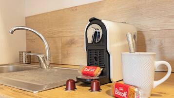 A kitchen with a sink, a toaster, a mug, and two biscuit packets.