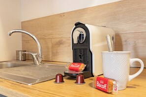 A kitchen with a sink, a toaster, a mug, and two biscuit packets. - Downtown, Studio Apartment with 4 air conditioning units, Wi-Fi, Canal+, and a washing machine (Bédarieux)