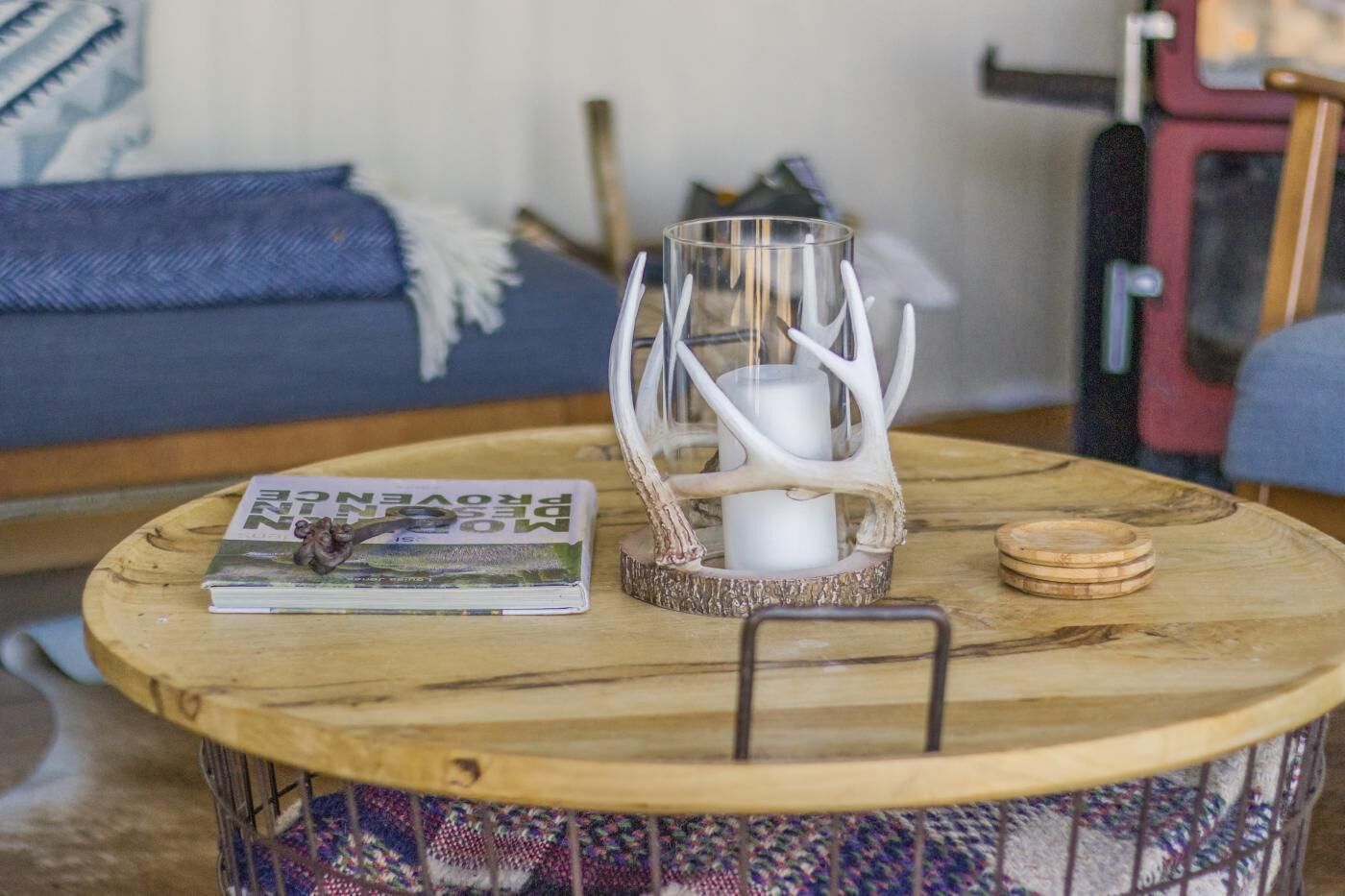 A round wooden table with a magazine, a candle, and a decorative item.