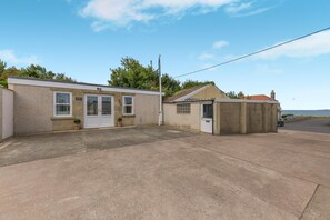 A two-story building with a flat roof, a small attached garage, and a paved driveway. - 2 Bed in Seahouses (oc-s42665) (Seahouses)