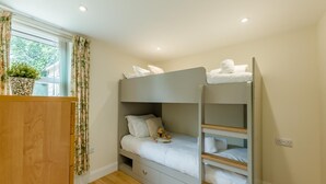 Ein Etagenbett mit Holz Kopfteil, ein Nachttisch und ein Fenster mit Vorhängen.