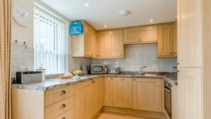 Eine Küche mit Holzausstattung, einer Mikrowelle, einem Toaster und einer Wanduhr.