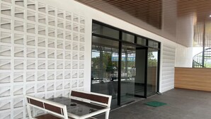 A modern interior with a glass partition, a wooden bench, and a concrete floor.