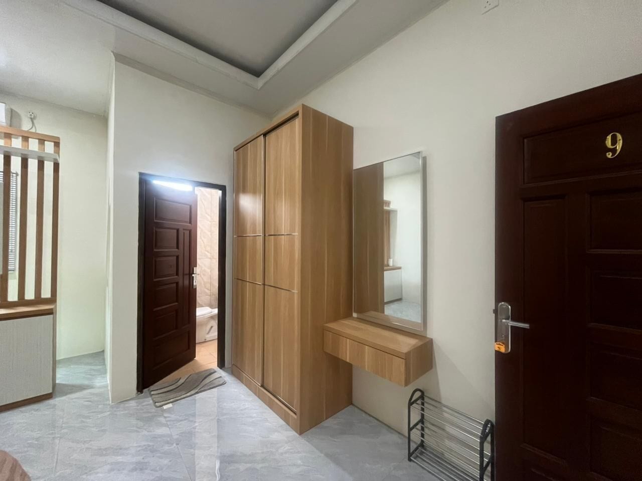 A hallway with a wooden wardrobe, a mirror, and a door with a number.