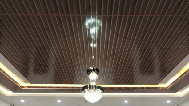 A spacious lobby with a wooden ceiling, a central chandelier, and a reception desk.