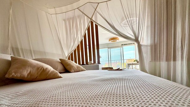 A bed with a canopy, pillows, and a view of the outside. - L’écrin Bleu – Sea View Apartment for 4 Guests (Le Cap d'Agde)