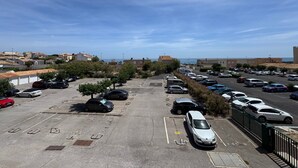 A parking lot with multiple cars, a clear sky, and buildings in the background. - L’écrin Bleu – Sea View Apartment for 4 Guests (Le Cap d'Agde)