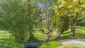 Un jardín bien cuidado con un sendero de grava, césped recién cortado y un banco de madera.