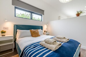 A modern bedroom with a large bed, a nightstand, a window, and a potted plant. - 1 Bed in St. Issey (oc-w42638) (Saint Issey)