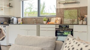 Moderni keittiö, jossa on sisäänrakennettu uuni, ikkuna ja ruokailutila, jossa on sohva.