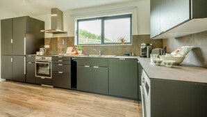 A modern kitchen with a built-in oven, a coffee maker, and a window with a view of greenery. - 1 Bed in St. Issey (oc-c42639) (Saint Issey)