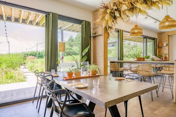 A dining area with a large table, chairs, and potted plants.