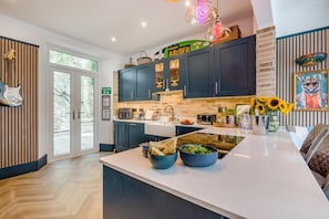 A modern kitchen with dark cabinets, a white countertop, and a fire exit sign.