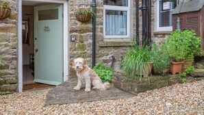 A stone building with a dog in front of a door labeled 'Bank House.' - 3 Bed in Reeth (oc-b42655) (Reeth)