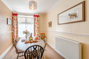 A dining room with a round table, chairs, a vase of flowers, and a framed picture on the wall. - 3 Bed in Reeth (oc-b42655) (Reeth)