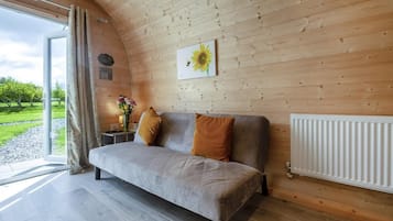 A cozy room with a sofa, a radiator, a window with curtains, and a sunflower painting on the wall.