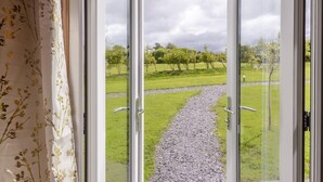 A view through a glass door with a gravel path leading to a green landscape.