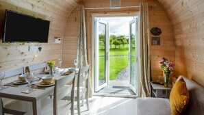 A cozy cabin with a dining area, a bed, and a fire exit sign.