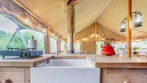 A kitchen with a sink, a stove, and a red kettle.