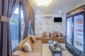 A modern living room with a sofa, a coffee table, and a refrigerator stocked with beverages.