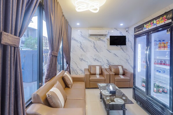 A modern living room with a sofa, a coffee table, and a refrigerator stocked with beverages.