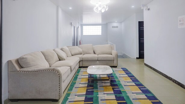 Una sala de estar moderna con un sofá seccional color beige, una mesa de centro de vidrio y un tapete geométrico colorido.