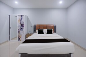 Ein Hotelzimmer mit einem Bett, einem Nachttisch, einem Spiegel und einer Tür.