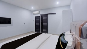 Habitación de hotel con cama, televisor de pantalla plana en la pared, armario y equipo de aire acondicionado.