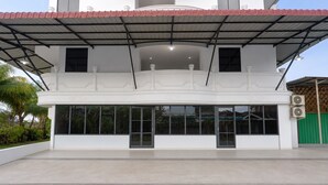 Un edificio de dos plantas con techo plano, ventanas amplias y una zona de entrada cubierta.