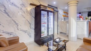 Un hall de hotel con pared de mármol, minibar, asientos de cuero y mostrador de recepción.