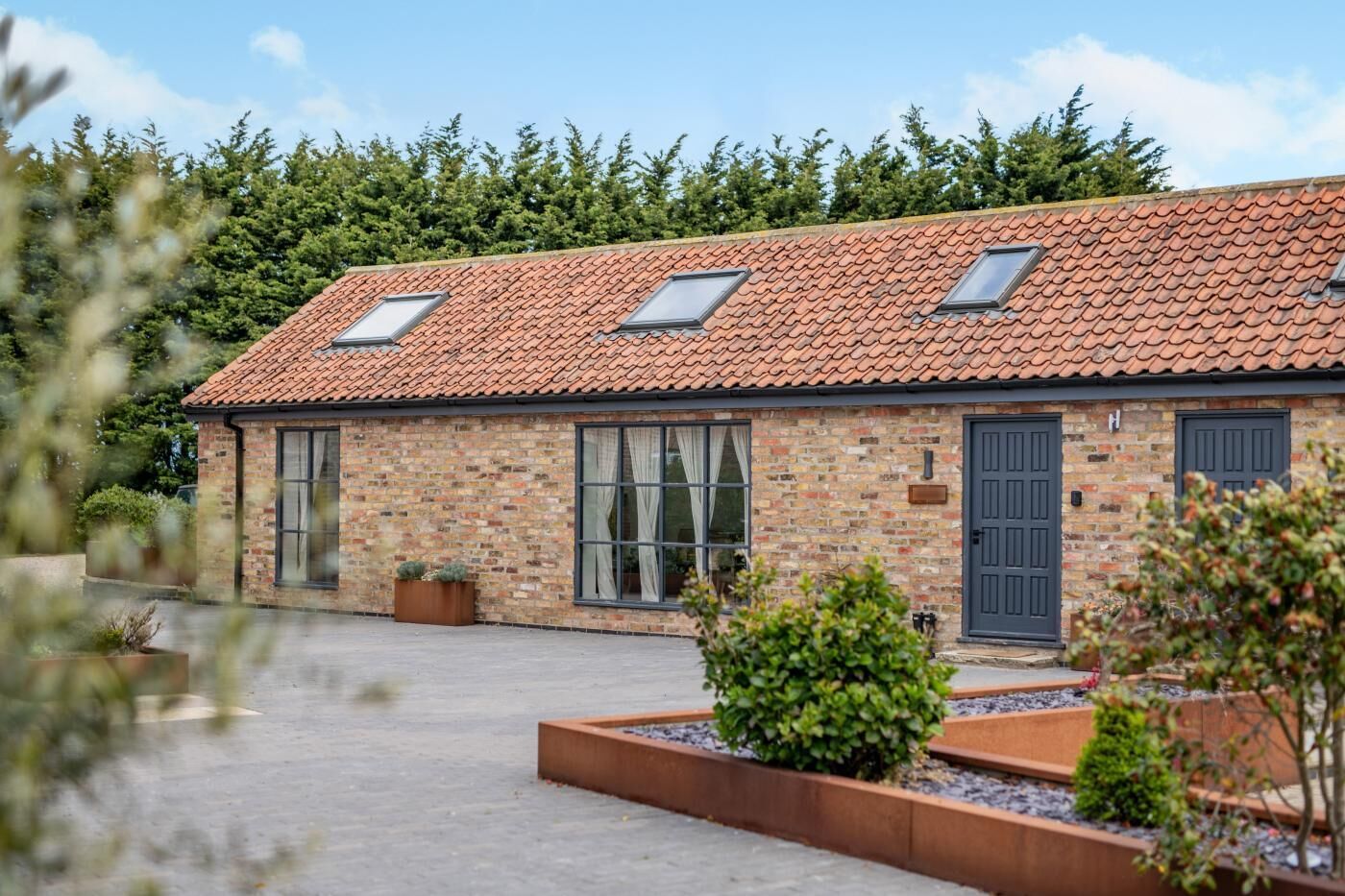 A brick building with a tiled roof, large windows, and a door.