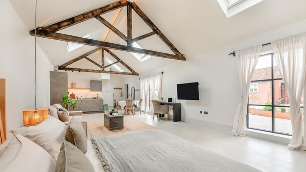 A spacious bedroom with a large bed, a dining area, and a kitchen in the background. - 1 Bed in Gembling (oc-s42456) (Gembling)
