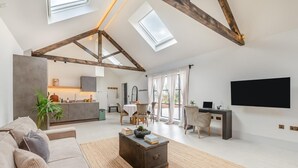 A spacious loft with high ceilings, exposed wooden beams, a kitchen area, a dining space, and a large TV mounted on the wall. - 1 Bed in Gembling (oc-s42456) (Gembling)