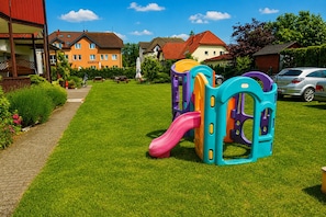 A playground with a slide and climbing structures, surrounded by well-maintained grass and a brick pathway. - Large Apartment in Dziwnowek, Close to the sea (Dziwnów)