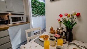 A breakfast setup with croissants, coffee, and juice on a table, a white chair, and a wall with green foliage. - 2 Bed in Warwick (oc-c41051) (Warwick)