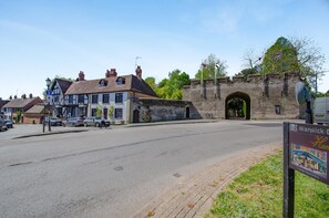 A street with a stone archway, traditional buildings, and a sign for Warwick Market Place.
