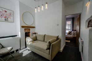 Ein modernes Wohnzimmer mit einer Couch, einem Kamin und einem Flur, der zu einem Schlafzimmer führt.