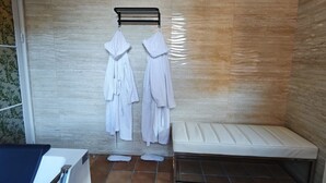 Ein Badezimmer mit Dusche, einer Sitzbank und Handtüchern an einem Wäscheständer.