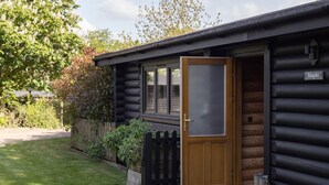 A log cabin with a wooden door open, a small porch, and a sign reading 'Maple'. - 2 Bed in Cretingham (oc-m42623) (Cretingham)