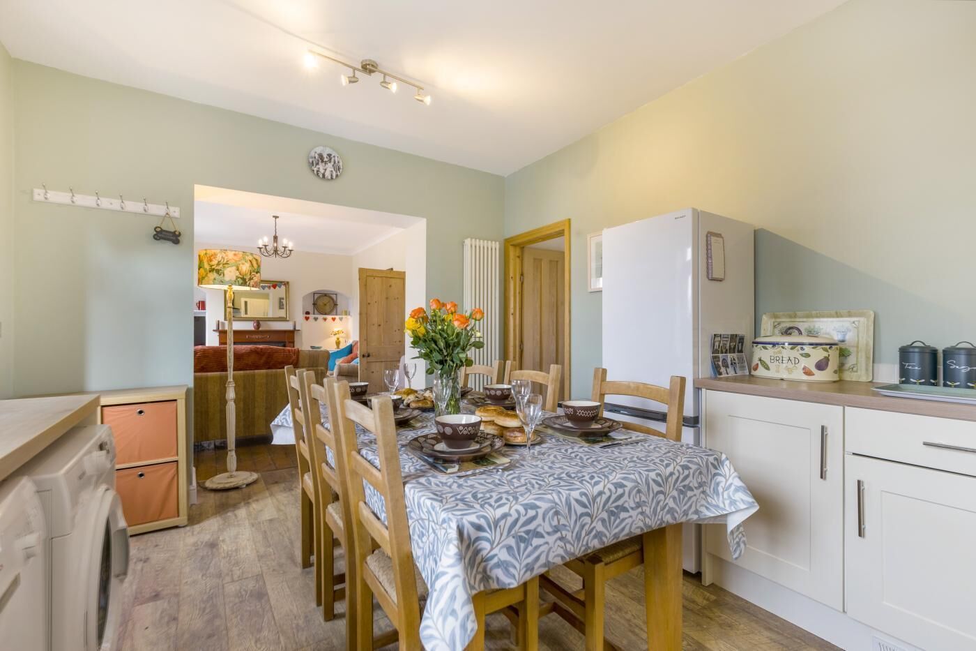 A compact kitchen with a dining table set for four, a refrigerator, and a small cabinet.